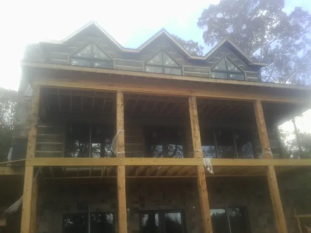 Dormers and porch framing on a large log home under construction — Roof Coating work by our crew in Cicero