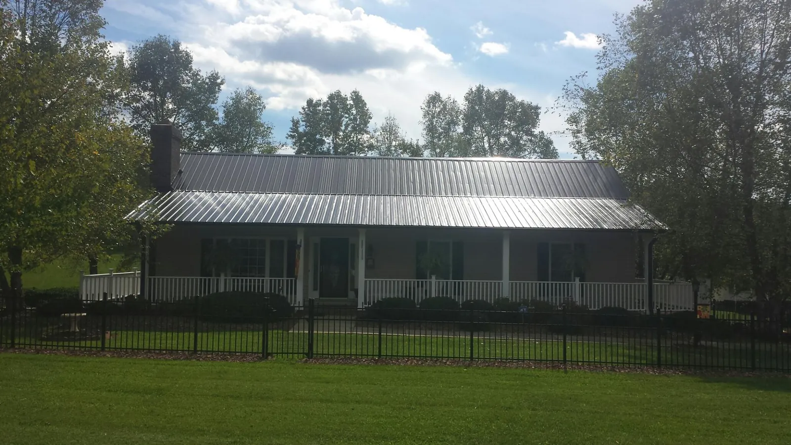 Gray metal roof on a brick ranch with a full width front porch — Gutter Guard Installation work by our crew in Cicero