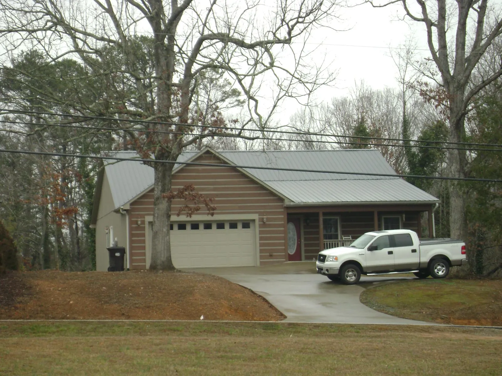 Gray metal roof on a log sided house with an attached two car garage in Cicero