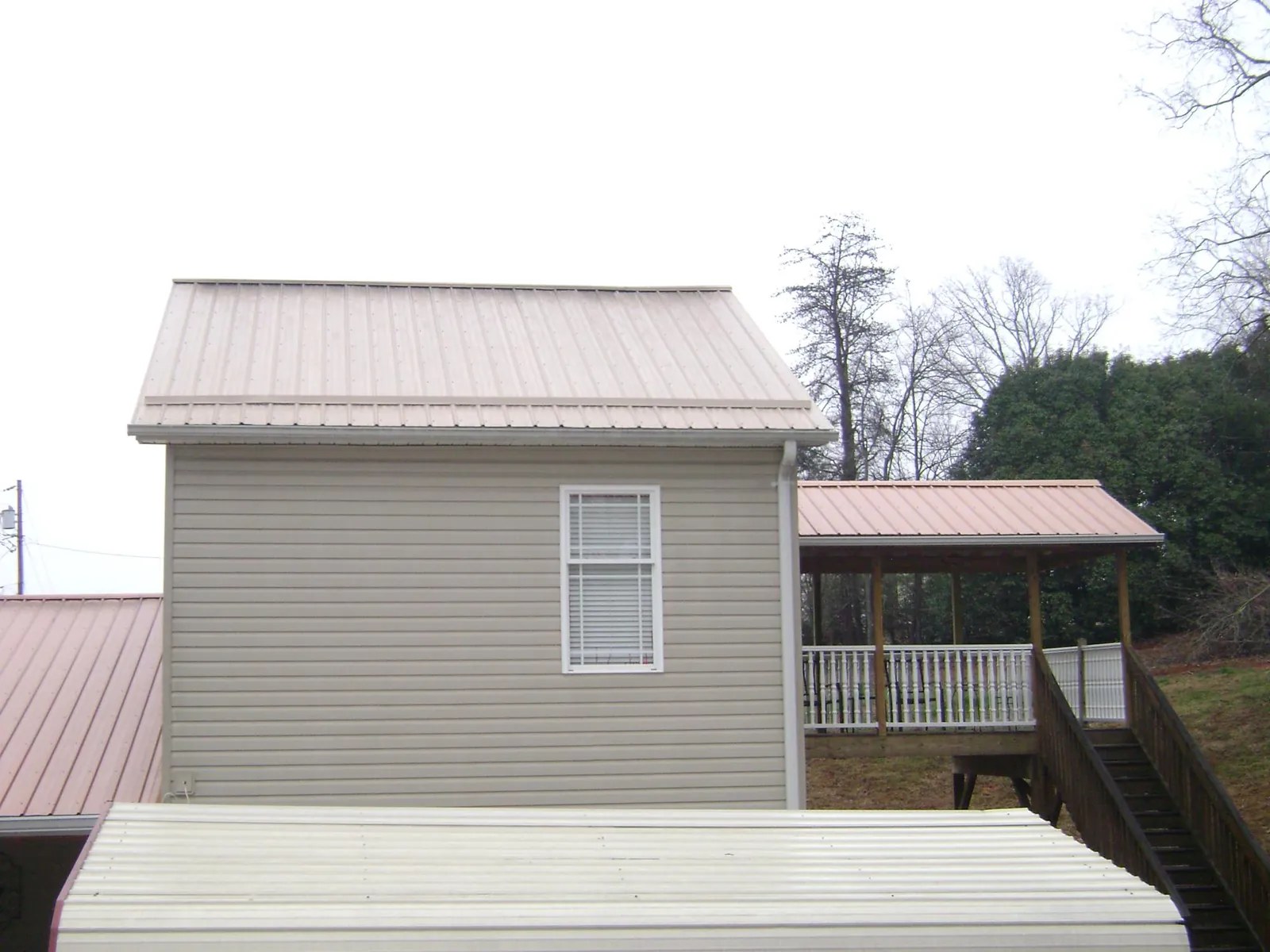 Tan metal roofs on a two story addition and attached porch, from a Roof Replacement job in Cicero